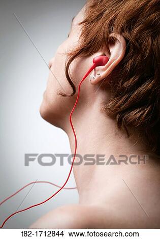 Picture - profile of face and neck of young woman listening to music on headphones. Fotosearch