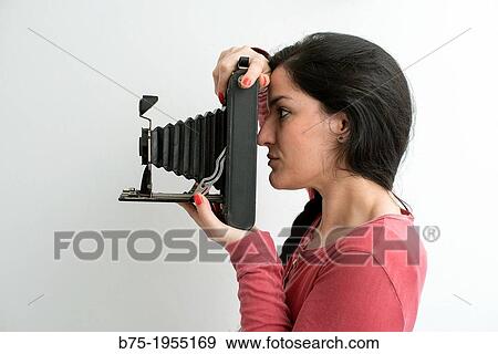 Profile of young woman looking through an old photographic camera View Large Photo Image Stock Photo - Profile of young woman looking through an old photographic camera. Fotosearch
