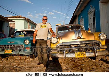 proud cuban man with his classic US car on a cobblestone street in the old town of Trinidad, Cuba, Caribbean. View Large Photo Image Stock Photo - proud cuban man with his classic US car on a cobblestone street in the old town of Trinidad, Cuba, Caribbean.. Fotosearch