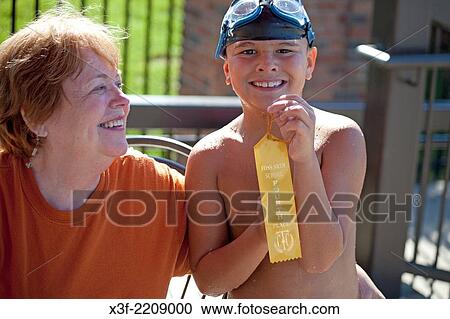 Stock Image - Proud Grandmother enjoying excited grandson displaying fourth place winner's ribbon. St Paul Minnesota MN USA.. Fotosearch