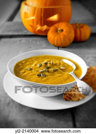 Picture - Pumpkin & Bacon Soup with a traditional Haloween pumpkin with a carved face.. Fotosearch
