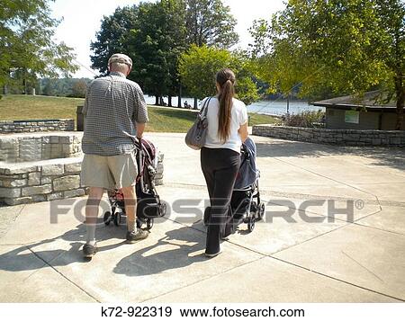 Pushing baby strollers through a park View Large Photo Image Stock Photo - Pushing baby strollers through a park. Fotosearch