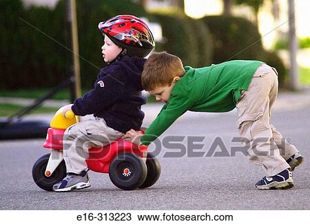 pushing boy on toy tricycle View Large Photo Image Stock Image - pushing boy on toy tricycle. Fotosearch