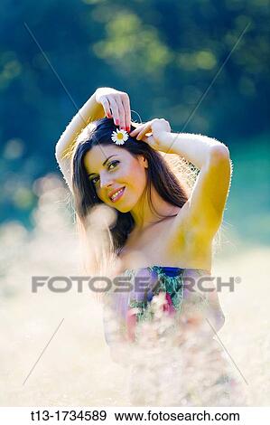 Stock Photo - Putting on a flower in hair young woman. Fotosearch