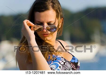 Putting on sunglasses young woman portrait View Large Photo Image Stock Image - Putting on sunglasses young woman portrait. Fotosearch