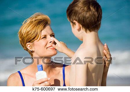 Stock Photo - Putting suntan lotion on mom's nose. Fotosearch