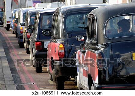 Stock Image - Queue of black London taxi cabs in traffic. Fotosearch