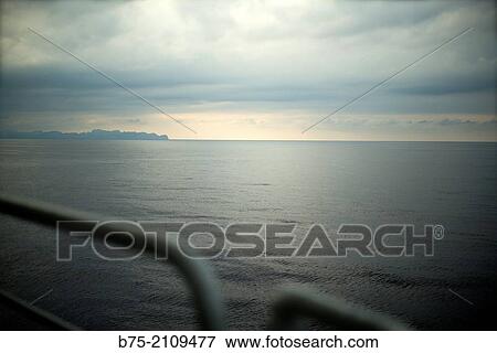 Railing of a Boat with Mallorca island in the horizon. Croosing the Mediterranean Sea from Ciutadella, Menorca to Alcudia, Mallorca, Balearic Islands, Spain View Large Photo Image Stock Photo - Railing of a Boat with Mallorca island in the horizon. Croosing the Mediterranean Sea from Ciutadella, Menorca to Alcudia, Mallorca, Balearic Islands, Spain. Fotosearch