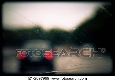 Stock Photo - Rain drops on windshield. Blurred view of cars on a highway.. Fotosearch