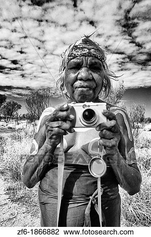Stock Image - Rare Photograph of Aboriginal Grandmother in Paint with Camera in the Outback Australia. Fotosearch