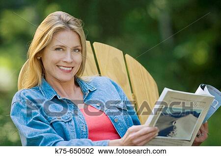 Stock Image - reading a magazine outdoors. Fotosearch