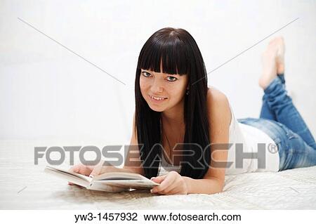 Stock Image - reading book - pretty brunette girl indoors. Fotosearch