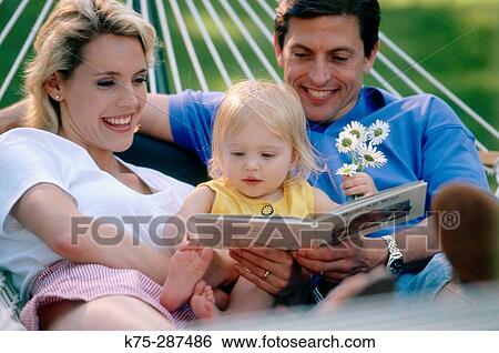 Stock Photograph - reading to their young daughter in a hammock. Fotosearch