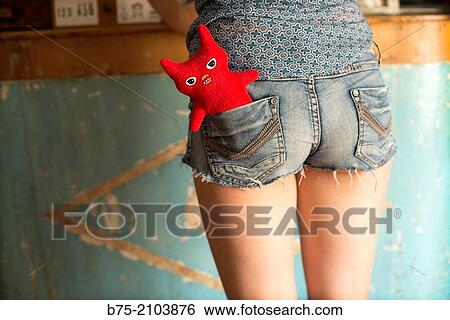 Rear view of a teenager girl with a red ugly doll in the shorts pocket. View Large Photo Image Stock Photograph - Rear view of a teenager girl with a red ugly doll in the shorts pocket.. Fotosearch
