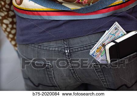 Picture - rear view of a woman with a map and a notebook in the back pocket. Fotosearch