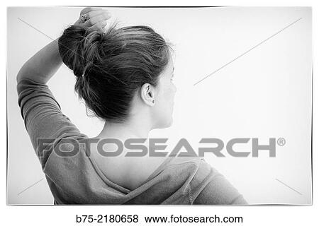 Stock Photo - Rear view of a young blond hair woman with a bun on the head and raised arm and hand in her hair.. Fotosearch