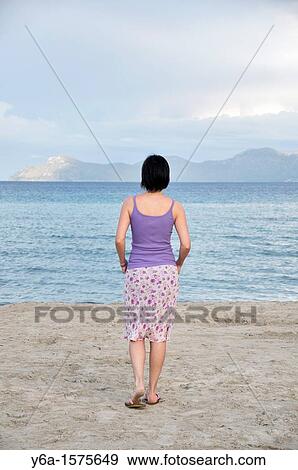 Rear view of mid adult woman standing on beach, Alcudia, Mallorca, Spain, Europe View Large Photo Image Stock Photo - Rear view of mid adult woman standing on beach, Alcudia, Mallorca, Spain, Europe. Fotosearch
