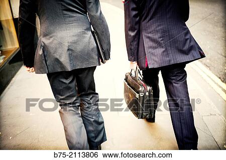 Rear view of two executive walking down the street with a briefcase in hand the City of London, England, UK, Europe. View Large Photo Image Stock Photograph - Rear view of two executive walking down the street with a briefcase in hand the City of London, England, UK, Europe.. Fotosearch