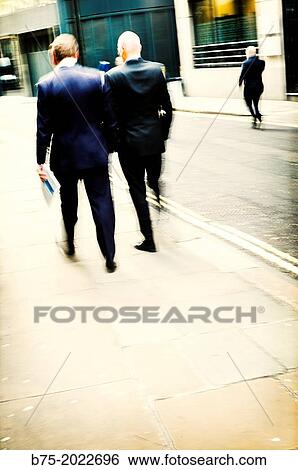 Rear view of two executives unrecognizable walking on a street in the City of London, England, UK View Large Photo Image Stock Photograph - Rear view of two executives unrecognizable walking on a street in the City of London, England, UK. Fotosearch
