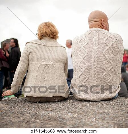 Stock Photo - Rear views of a man and woman wearing matching beige cardigans. Fotosearch