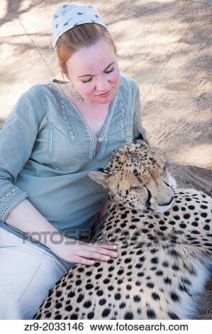 Red-haired woman lying beside a cheetah in the Karoo desert of South Africa. View Large Photo Image Stock Photograph - Red-haired woman lying beside a cheetah in the Karoo desert of South Africa.. Fotosearch