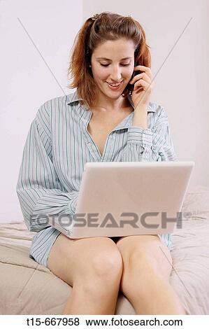 Red headed woman working on laptop and on phone on bed in pajamas View Large Photo Image Stock Photo - Red headed woman working on laptop and on phone on bed in pajamas. Fotosearch