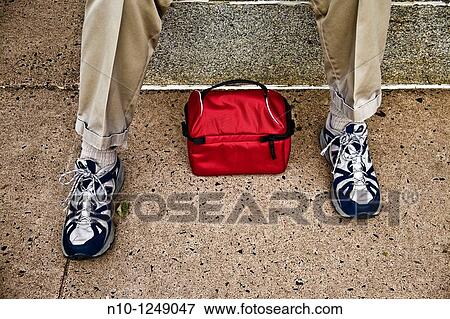 Red lunch container by a man's feet View Large Photo Image Stock Photo - Red lunch container by a man's feet. Fotosearch