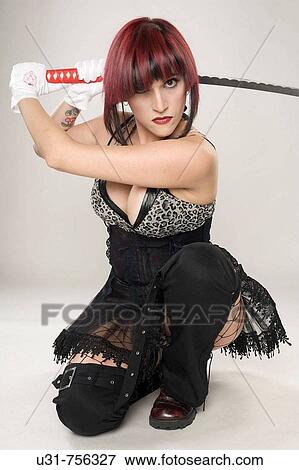 Stock Photo - Redhaired girl on Japanese fighter outfit holding a sword looking menacing at the camera. Fotosearch