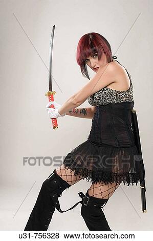 Stock Photo - Redhaired girl on Japanese fighter outfit holding a sword looking menacing at the camera. Fotosearch