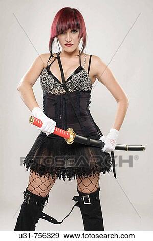 Stock Photo - Redhaired girl on Japanese fighter outfit holding a sword looking menacing at the camera. Fotosearch