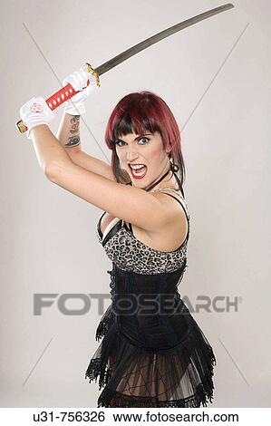 Stock Photograph - Redhaired girl on Japanese fighter outfit holding a sword looking menacing at the camera. Fotosearch