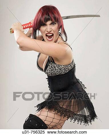 Stock Photography - Redhaired girl on Japanese fighter outfit holding a sword looking menacing at the camera. Fotosearch