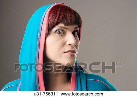 Stock Image - Redhaired trendy girl wearing a hood with makeup on one eye. Fotosearch