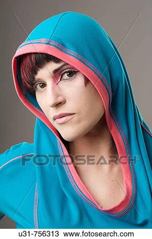 Stock Image - Redhaired trendy girl wearing a hood with makeup on one eye. Fotosearch