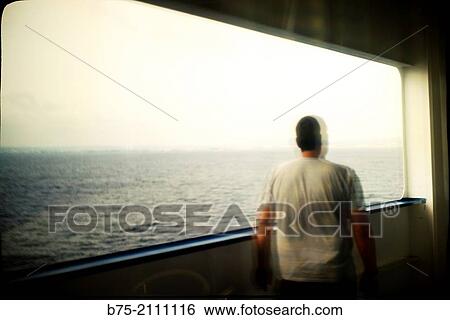 Reflection in a window of a passenger boat of a man leaning on the railing of the deck overlooking the sea. View Large Photo Image Stock Photograph - Reflection in a window of a passenger boat of a man leaning on the railing of the deck overlooking the sea.. Fotosearch