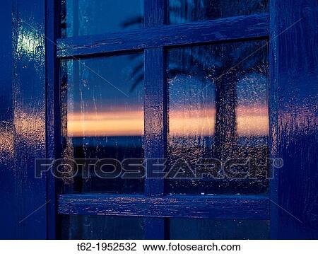Stock Image - Reflection of the sun in the blue window.. Fotosearch