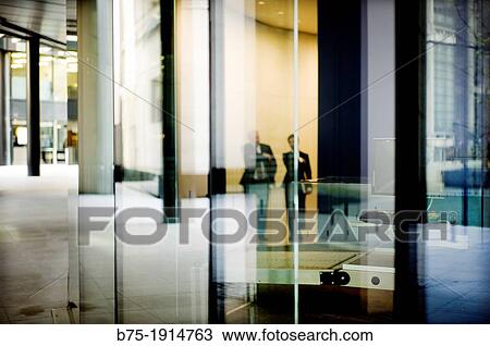 reflection of two executives walking through the lobby of an office building in City of London, England, UK View Large Photo Image Stock Image - reflection of two executives walking through the lobby of an office building in City of London, England, UK. Fotosearch