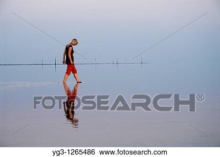 Reflection of woman walking in Wadden sea, Juist, Germany View Large Photo Image Stock Photograph - Reflection of woman walking in Wadden sea, Juist, Germany. Fotosearch