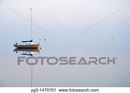 Stock Image - Reflections of sailboats in Wadden Sea, Juist, Germany. Fotosearch
