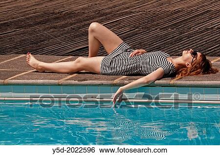 relaxed young woman in stripped dress laying at the poolside, Geneva, Switzerland View Large Photo Image Stock Photograph - relaxed young woman in stripped dress laying at the poolside, Geneva, Switzerland. Fotosearch