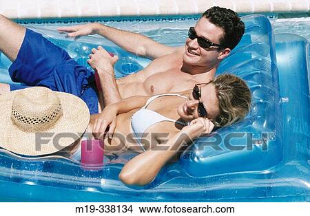 Picture - relaxing in the pool talking on cel phone. Fotosearch