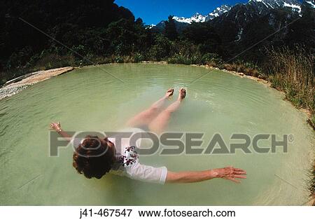 Stock Photo - Relaxing in Welcome Flat hot pools. Natural thermal pools. Edge of Alpine Fault. Copland Valley. Westland National Park. South Island. New Zealand.. Fotosearch
