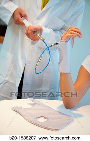 Stock Photo - Researcher placing a patient splint prototype built with variable stiffness textile and automatic generation by vacuum lamination. Fotosearch