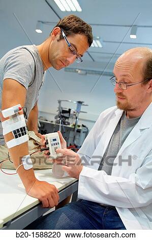 Stock Image - Researcher placing multipad electrodes in the control arm for the stimulation model for sensor signals. Fotosearch