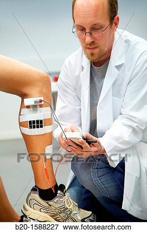 Stock Photo - Researcher placing multipad electrodes in the leg to control stimulation models of sensor signals. Fotosearch