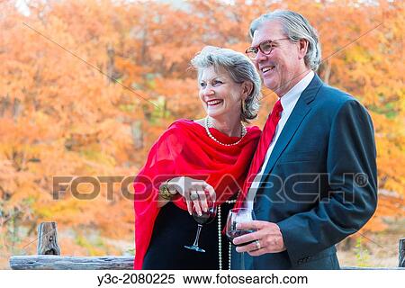 Retired couple in elegant formal outfit with dress and suit enjoying wine and each others company at outdoor party. View Large Photo Image Stock Photography - Retired couple in elegant formal outfit with dress and suit enjoying wine and each others company at outdoor party.. Fotosearch