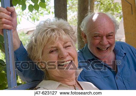 Retired couple sitting together smiling into camera View Large Photo Image Stock Photo - Retired couple sitting together smiling into camera. Fotosearch