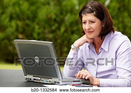 Retired woman using laptop computer in her garden View Large Photo Image Picture - Retired woman using laptop computer in her garden. Fotosearch