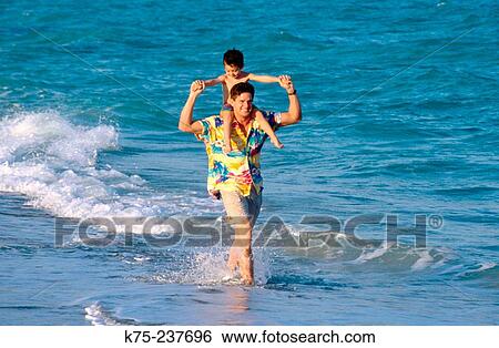 Stock Photograph - Riding piggyback at the beach. Fotosearch