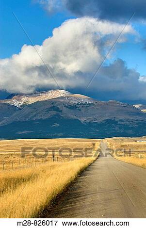 Stock Photo - Road on the Montana plains near the Rocky Mountain Front Ranges of Glacier National Park USA. Fotosearch
